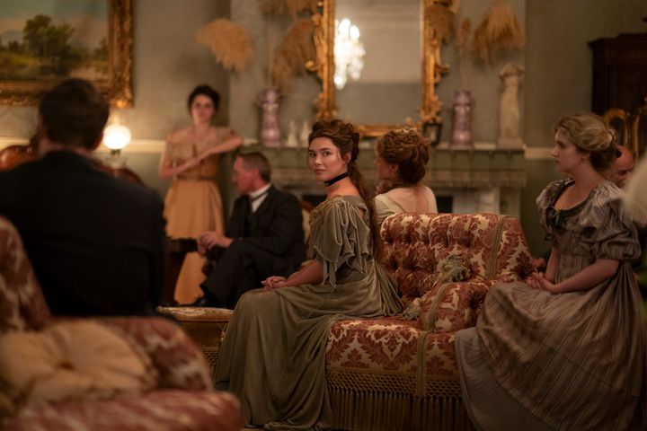 A woman in a green dress sits among guests in an ornate parlor in East of Eden.