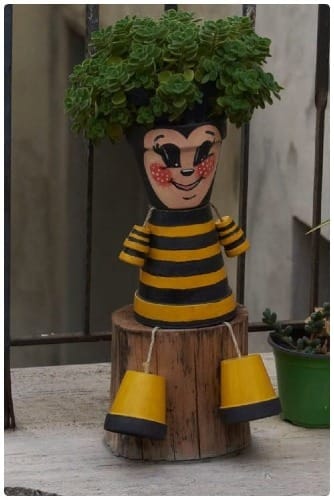 A creative planter painted with a smiling face holds a thriving plant adorning a doorstep in Salice [Photo taken October 2024]