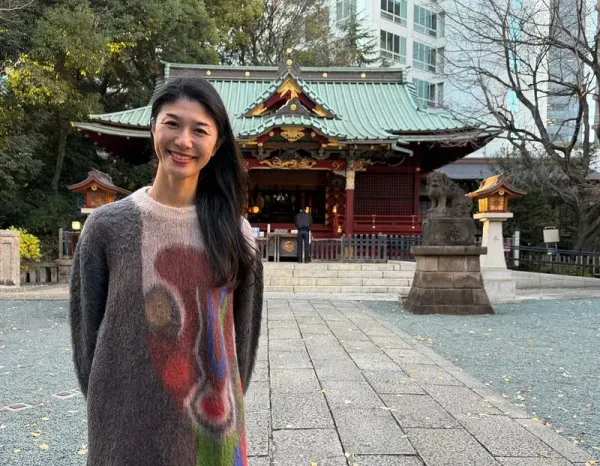 Masako Shiba standing in front of a red Japanese shrine in Tokyo