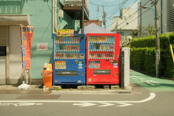 Two colorful vending machines on a city street corner in Japan