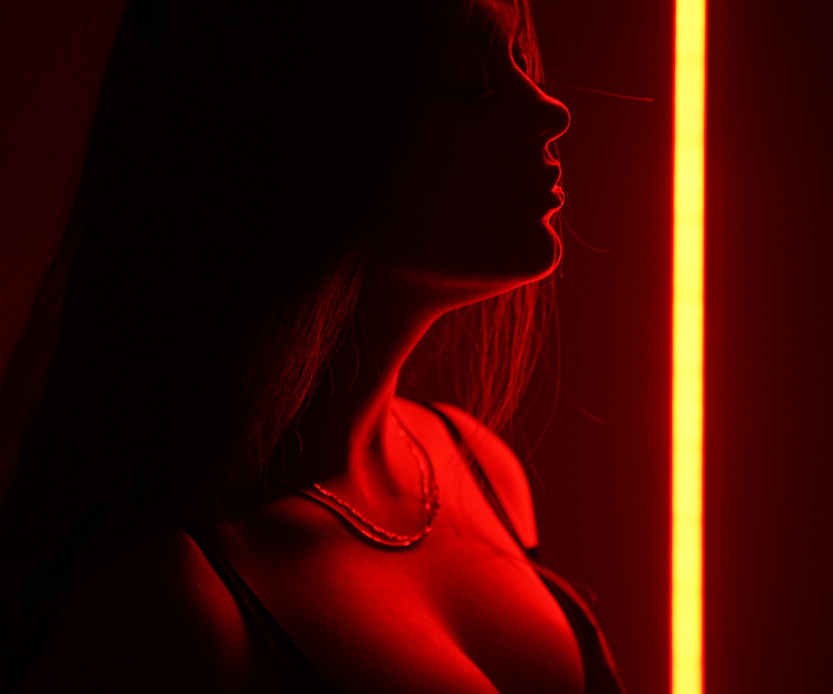 Red light shines on a woman in a scarlet gown.