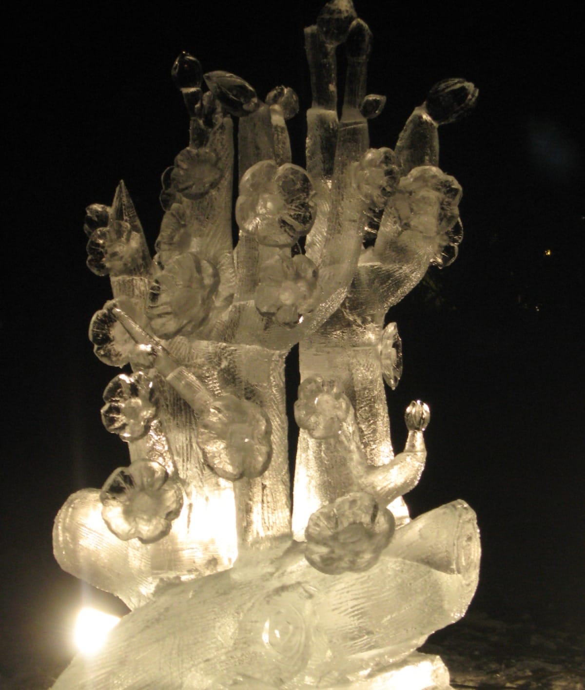 Intricate ice sculpture of a stylized tree with blossoms illuminated at night in Fairbanks Alaska