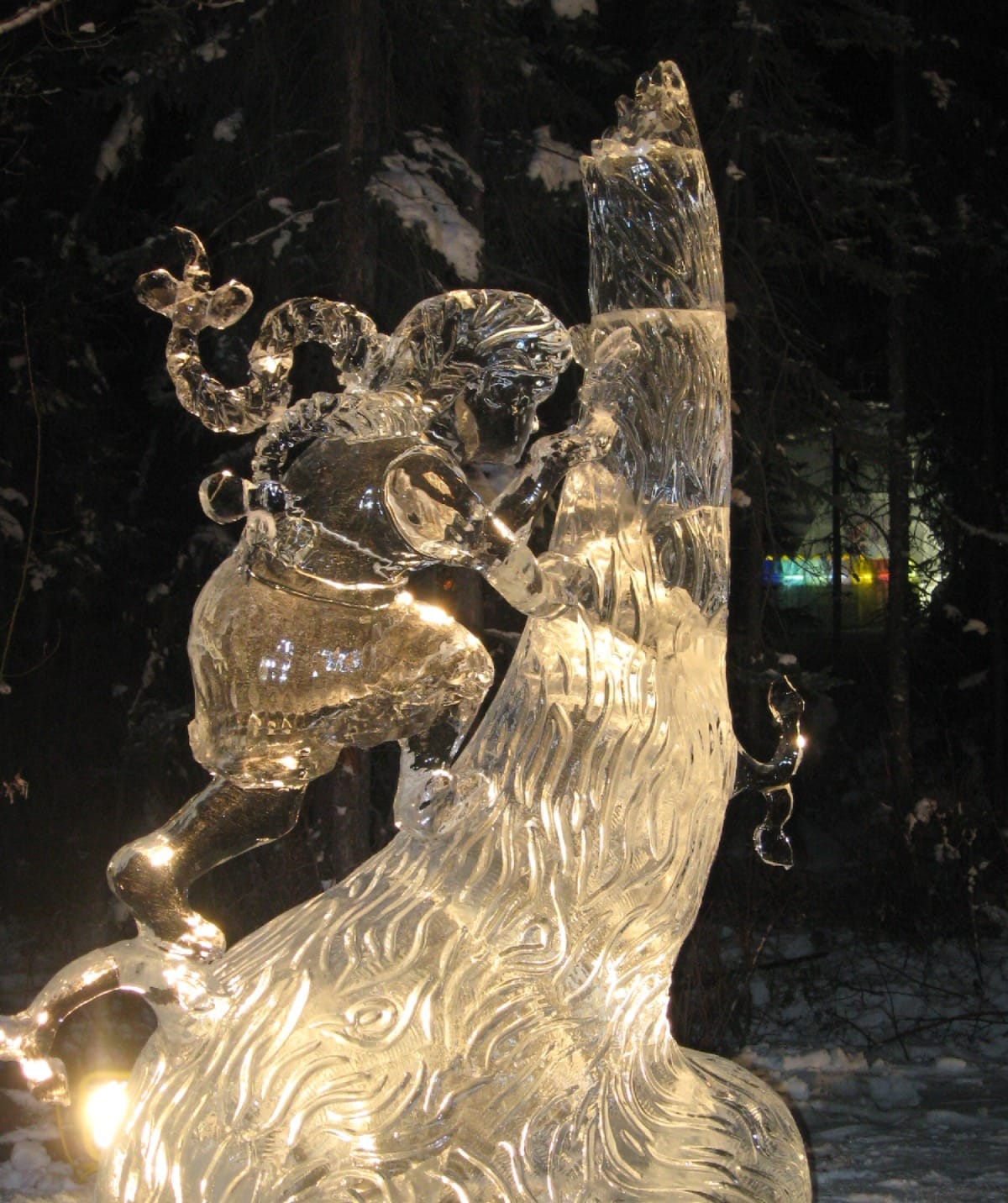 Detailed ice sculpture of a girl climbing a tree lit at night in an Alaskan forest setting