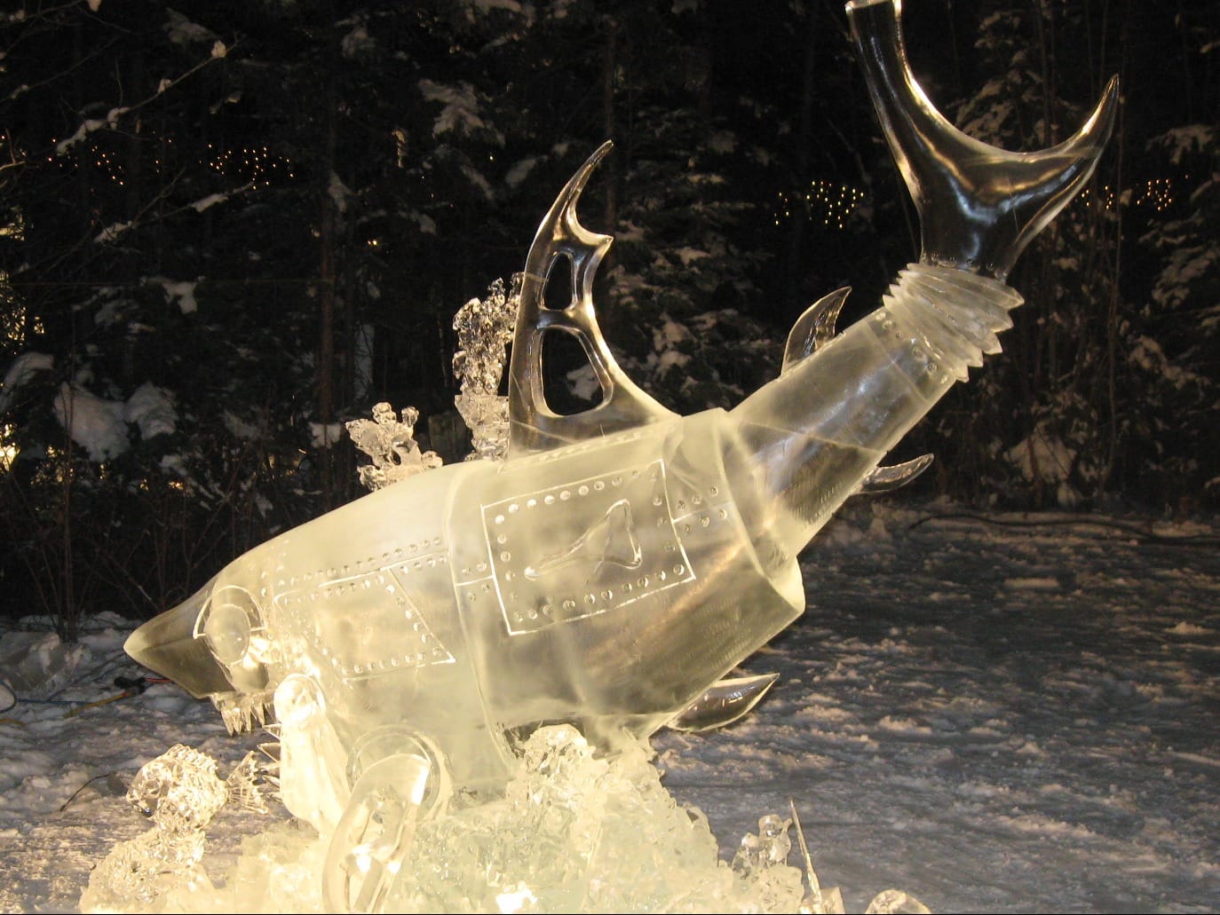 Creative ice sculpture of a robotic shark with mechanical details displayed outdoors at night