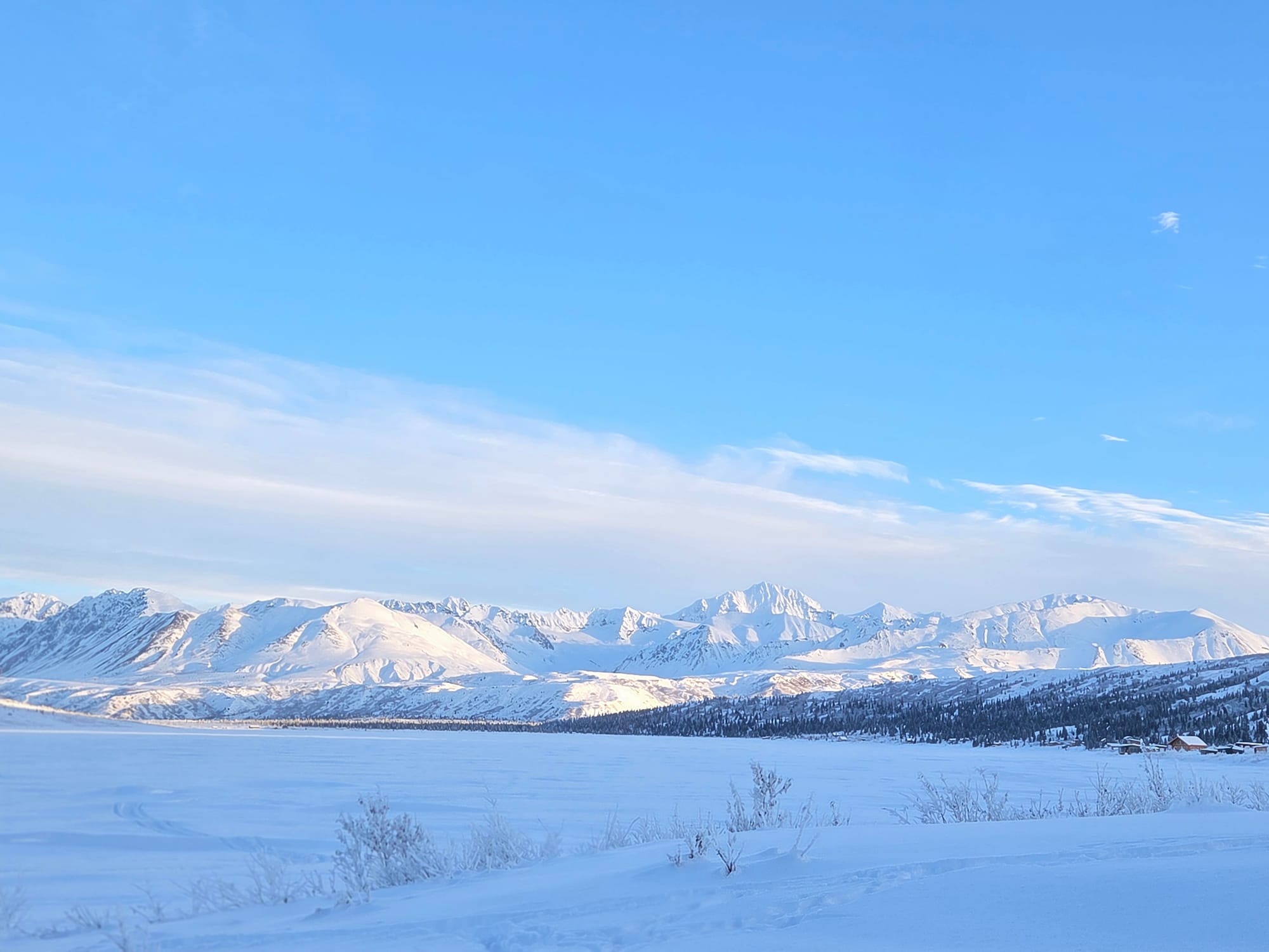Snow-covered Alaska mountains stretching across a remote backcountry landscape under soft daylight.
