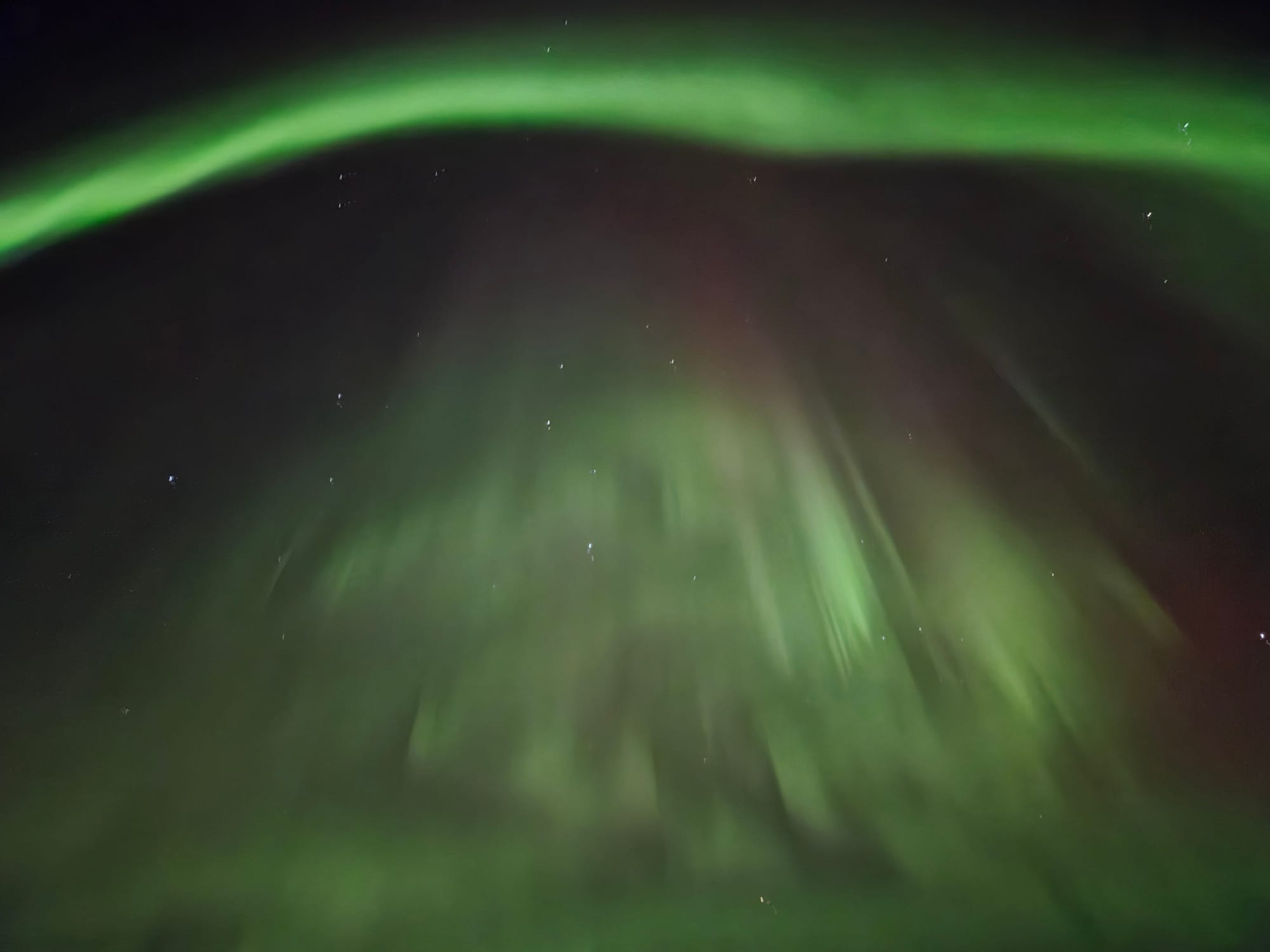 Green Northern Lights sweeping across the star-filled Alaska night sky