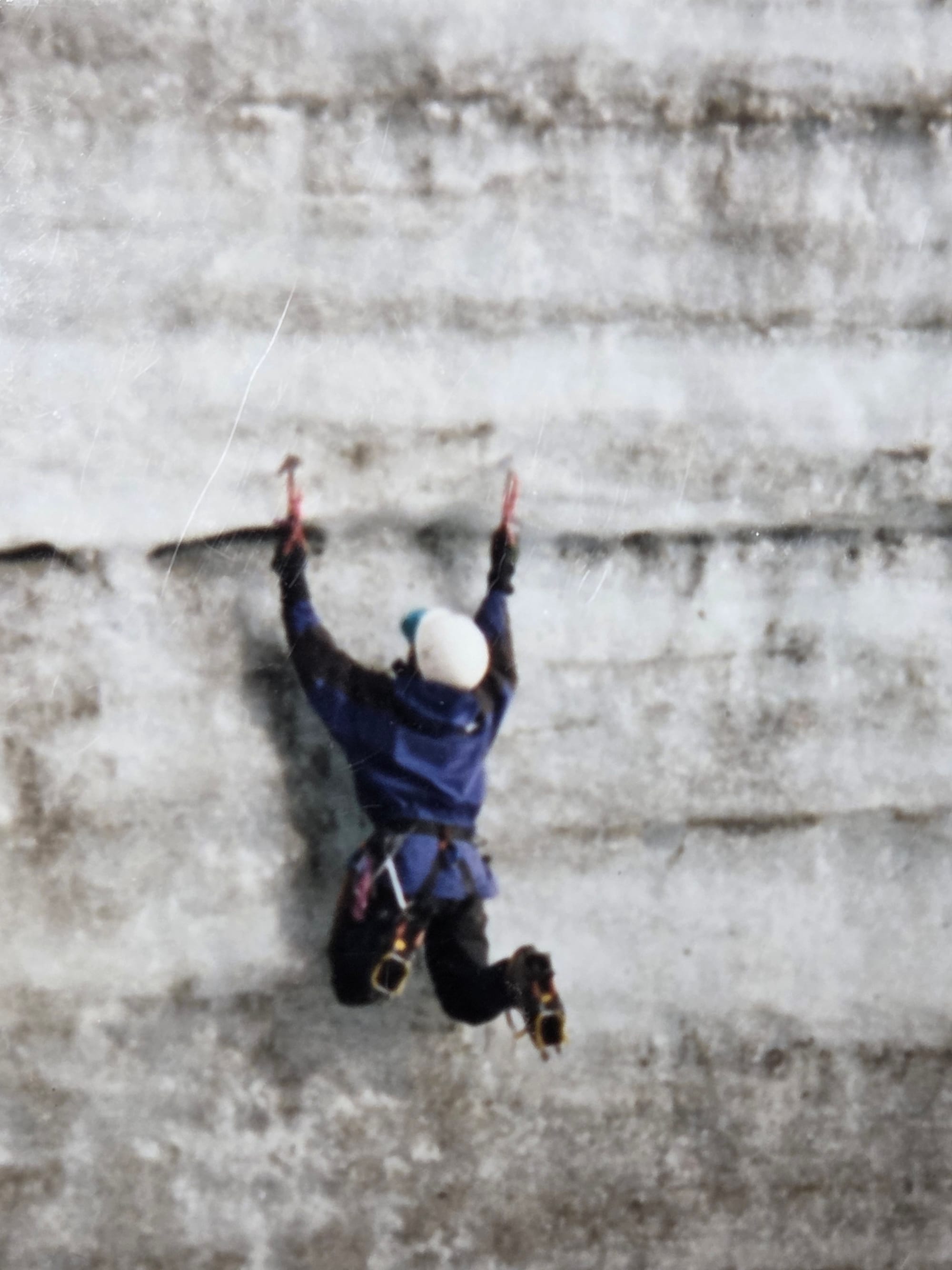 Ice climber ascending a frozen ice wall in Alaska