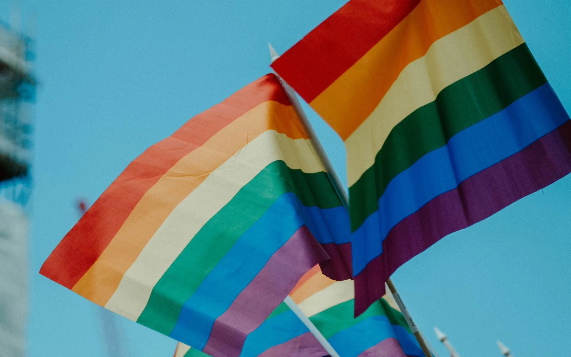 Two Pride flags waving in the sun