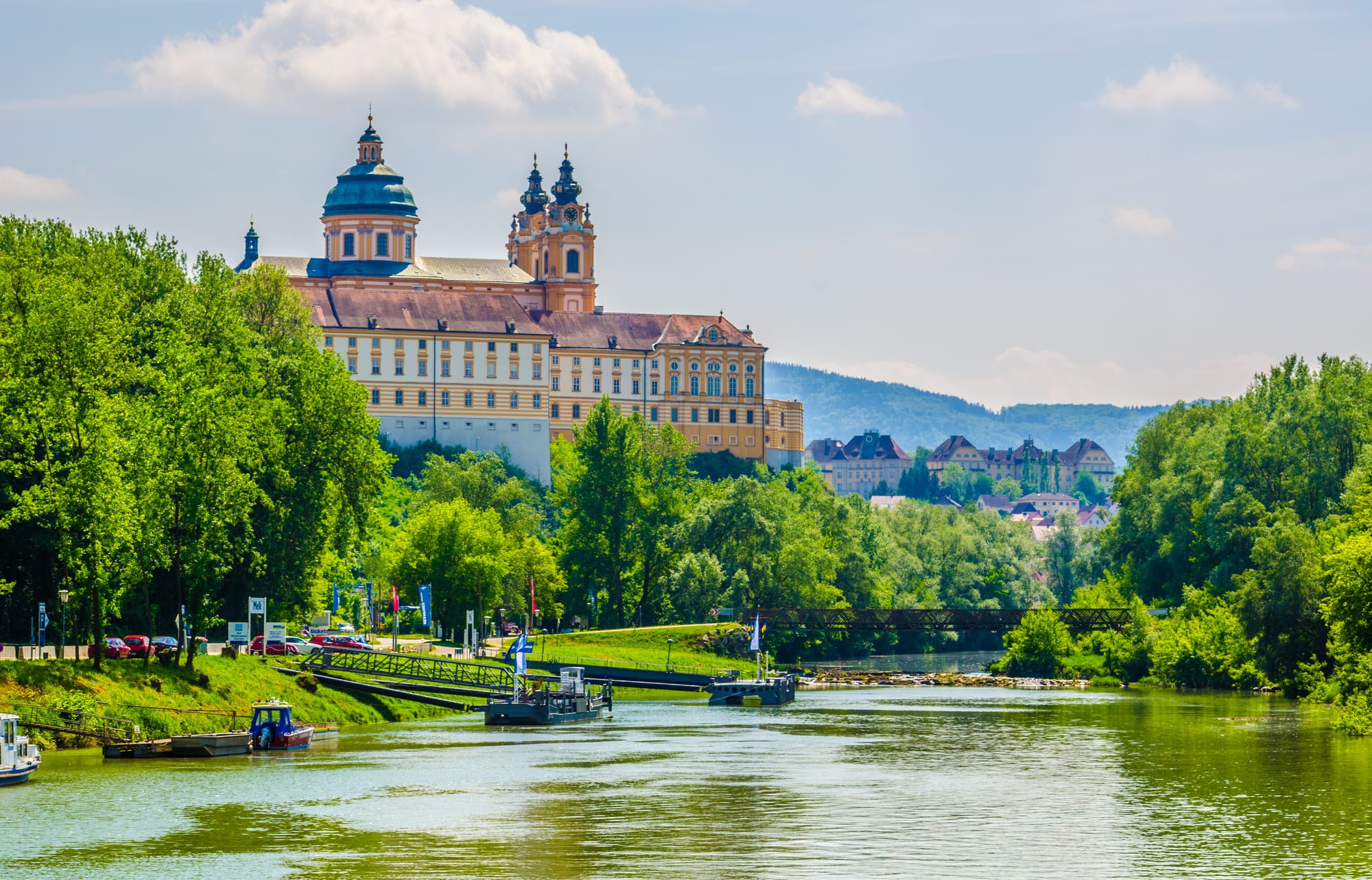 An image of a river with green trees on both banks and a medieval abbey in the background