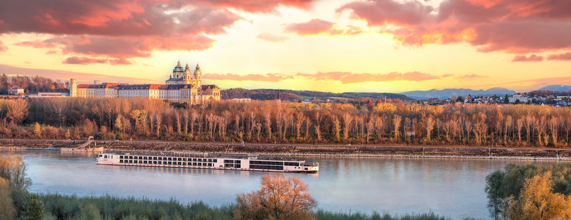 A river cruise ship sailing past Melk during an evening in autumn