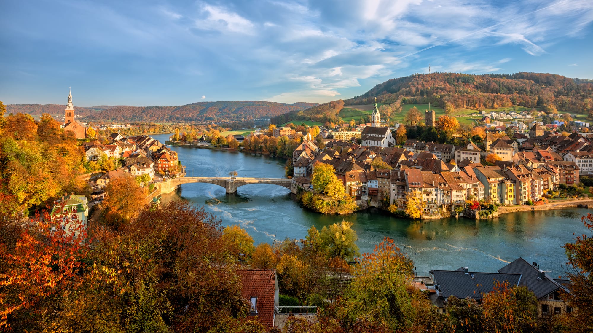 A bend in the Rhine river with orange-leaved trees either side and a small town