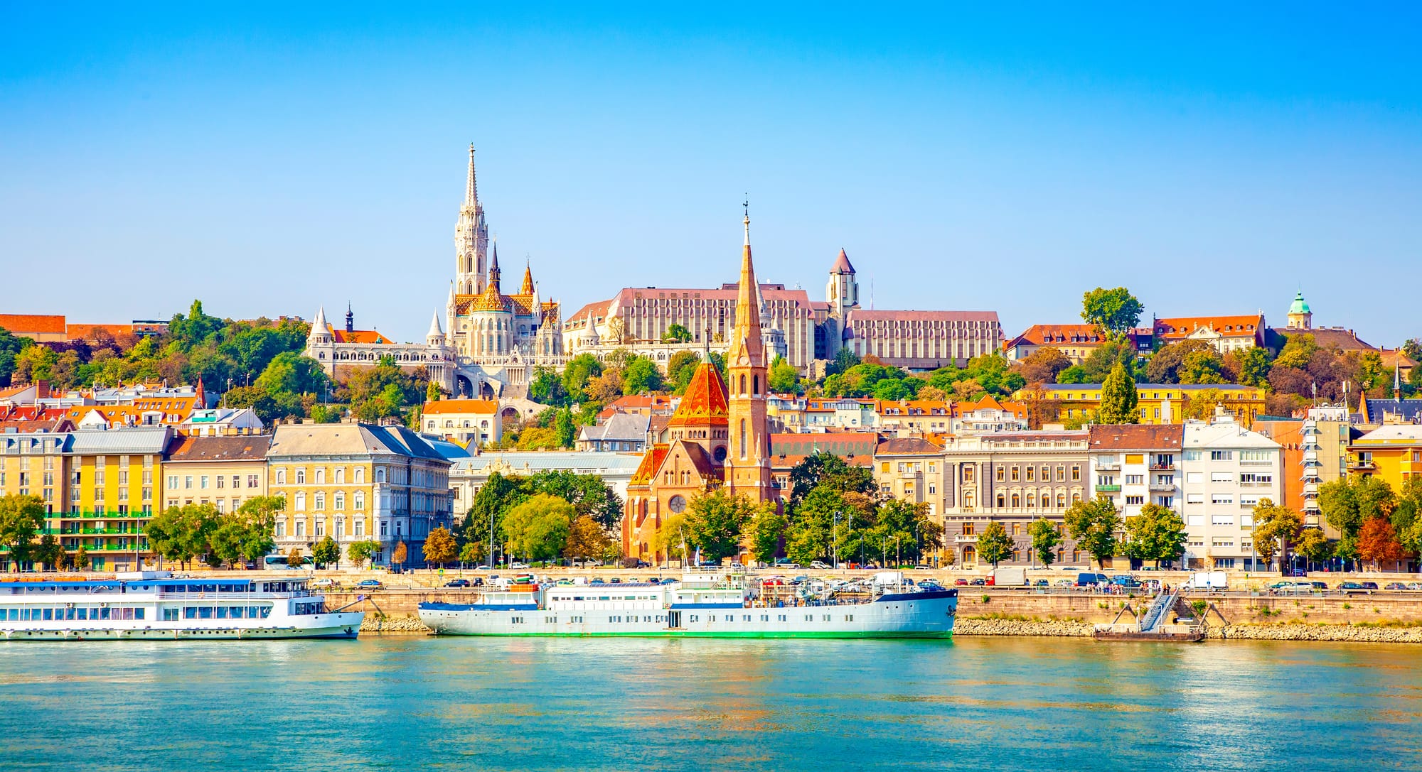 The Budapest skyline from across a river with boats on the water