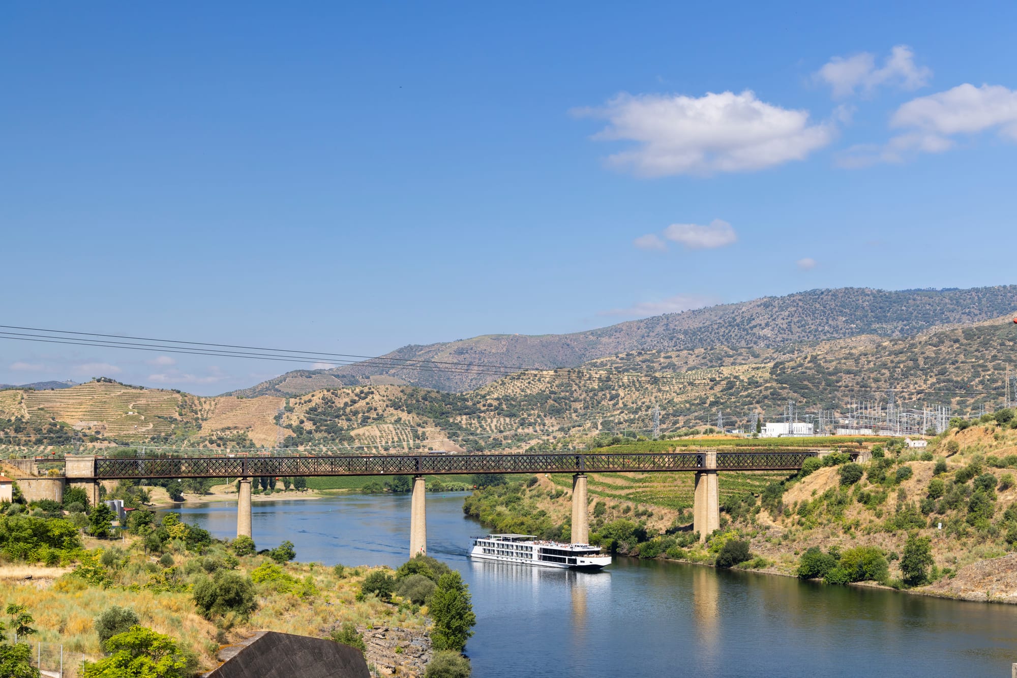 A river cruise ship passing under a railway bridge on the Douro