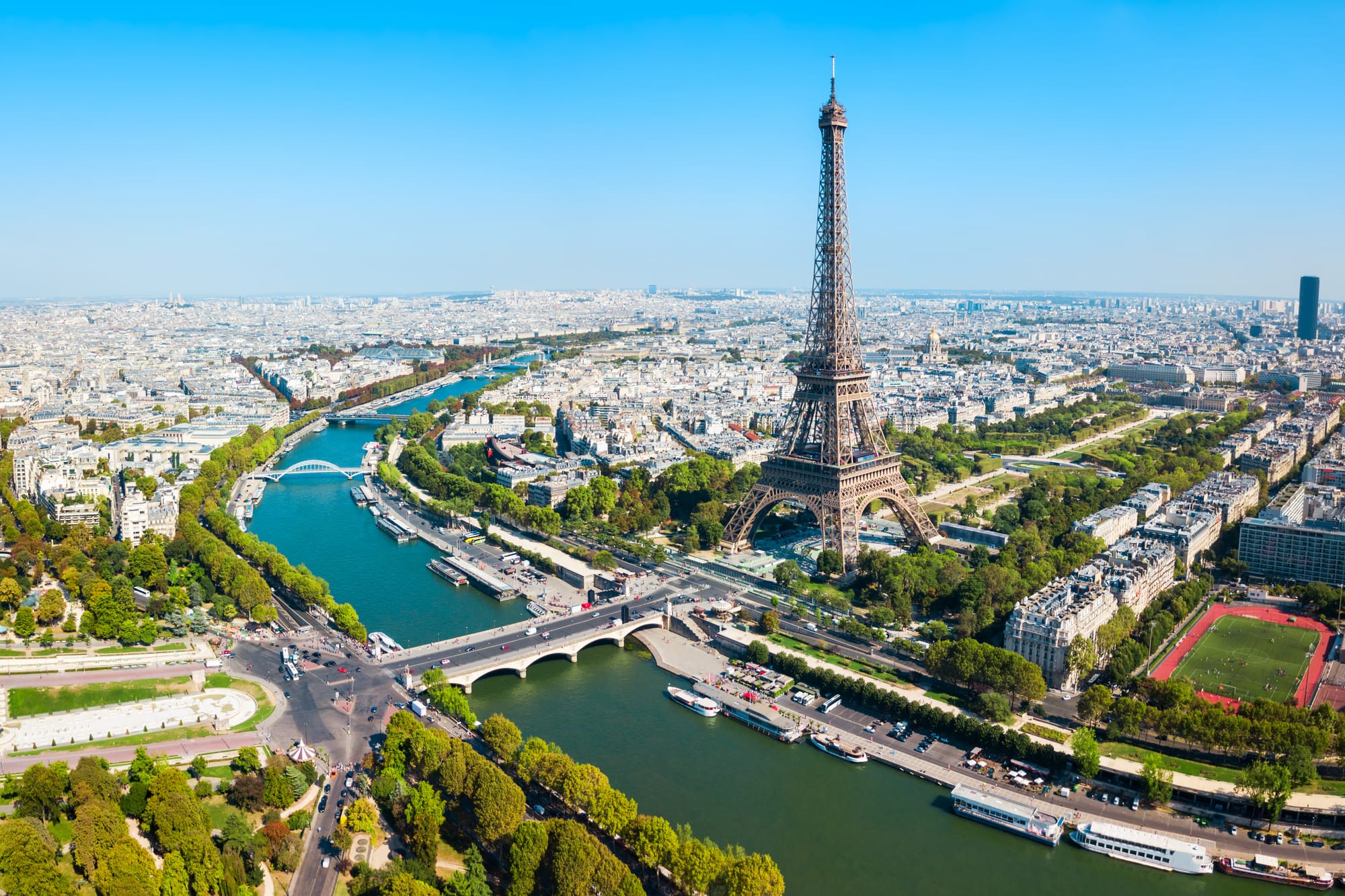 An image of Paris and the Eiffel tower from above, with the Seine cutting through the city