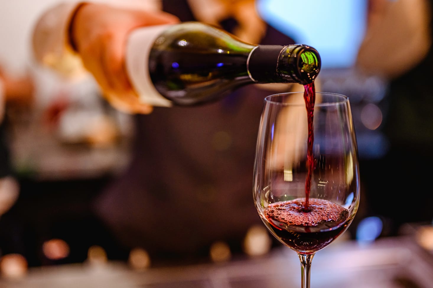 An image of a waiter pouring some red wine in a wine glass