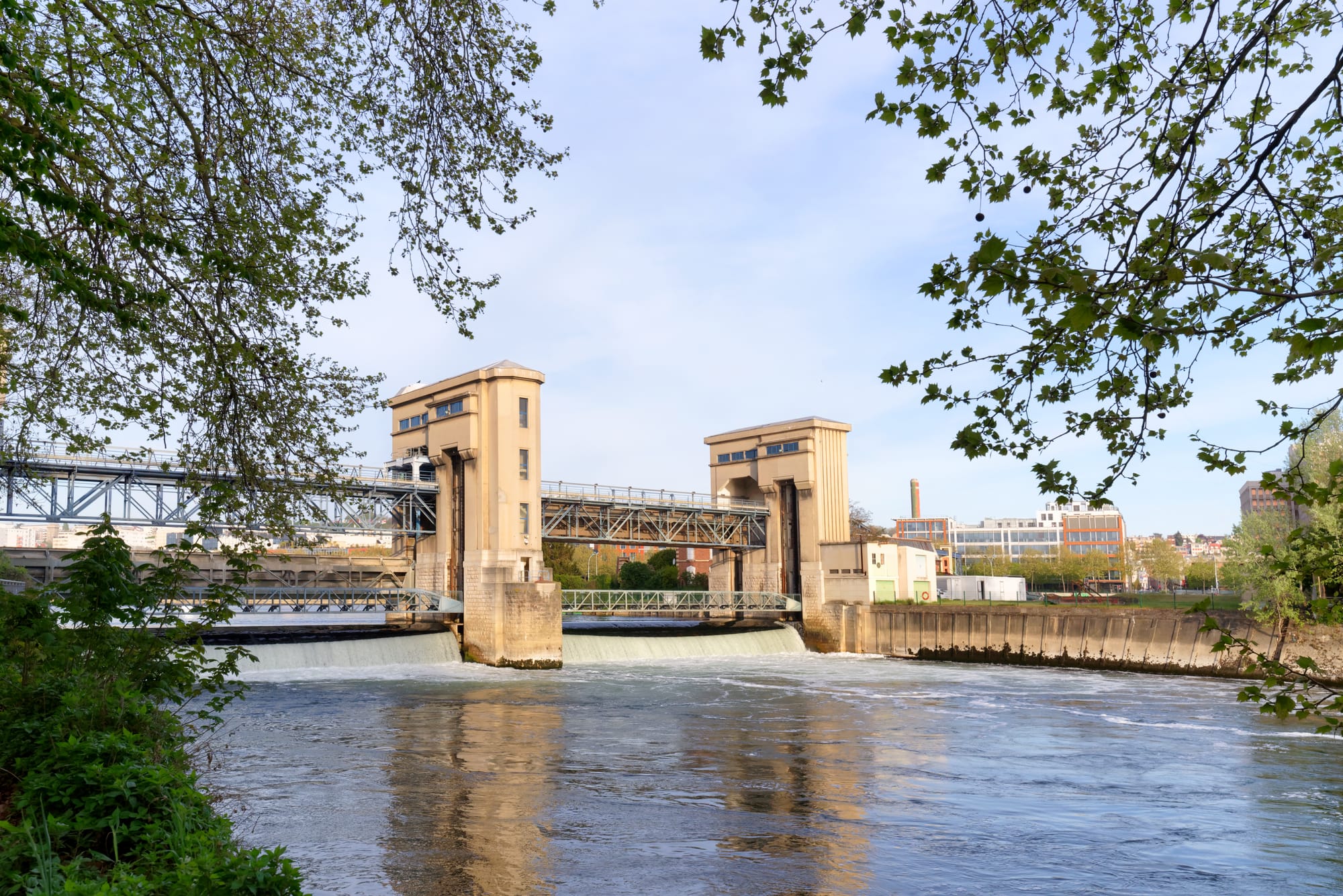 A modern river lock on the Seine, with foliage in the foreground
