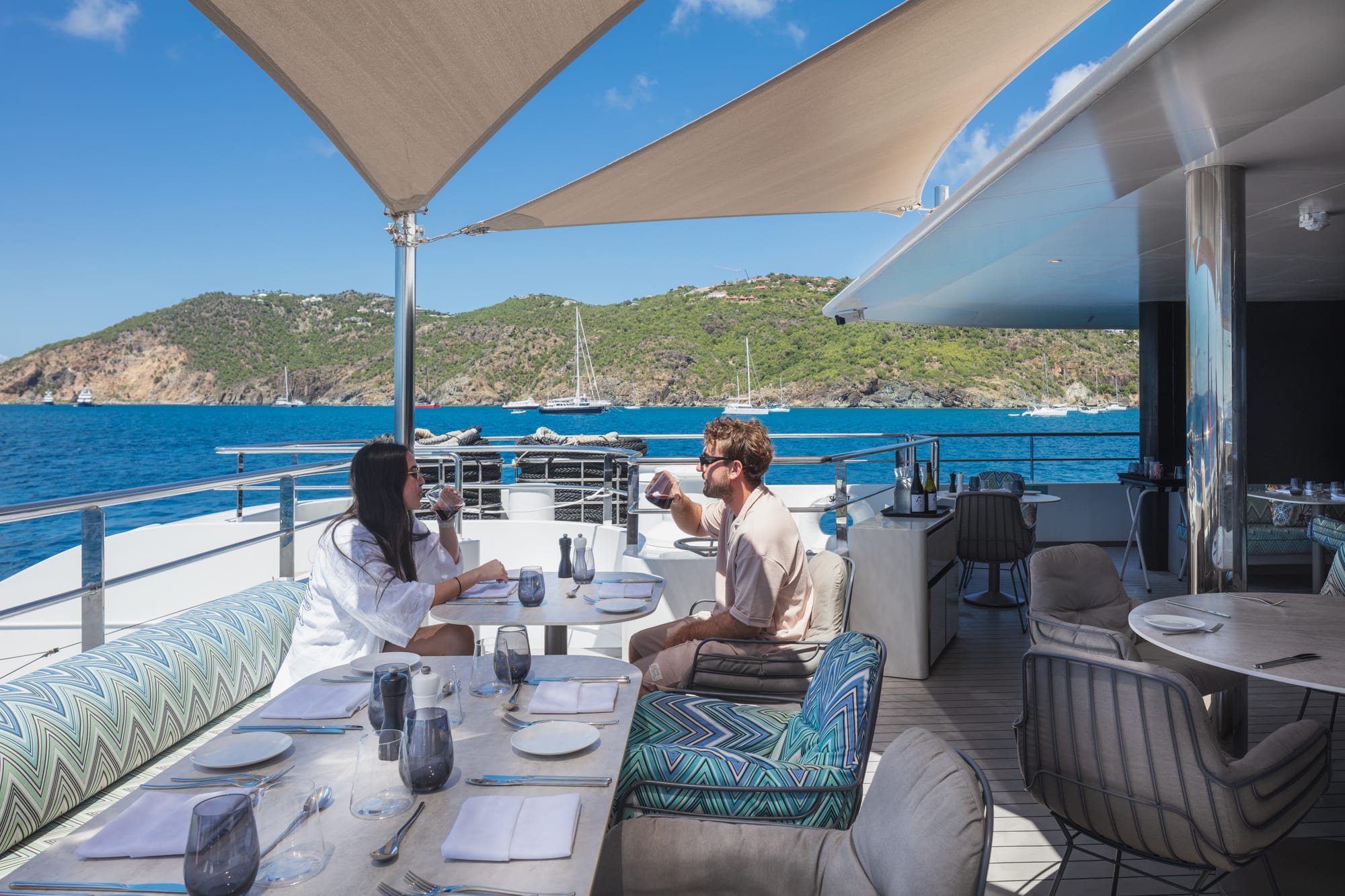 A couple enjoying drinks on an aft-facing lounge area on a luxury cruise ship on a sunny day