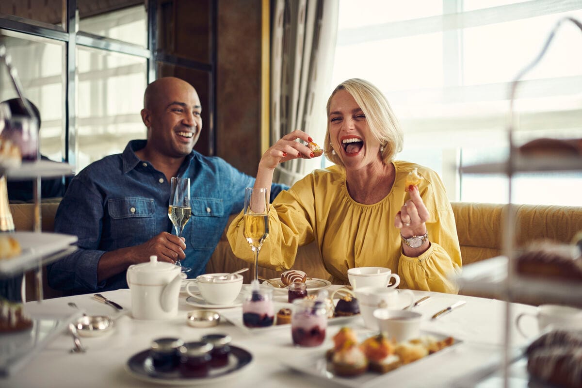 A man and a woman enjoying an afternoon tea service with Champagne