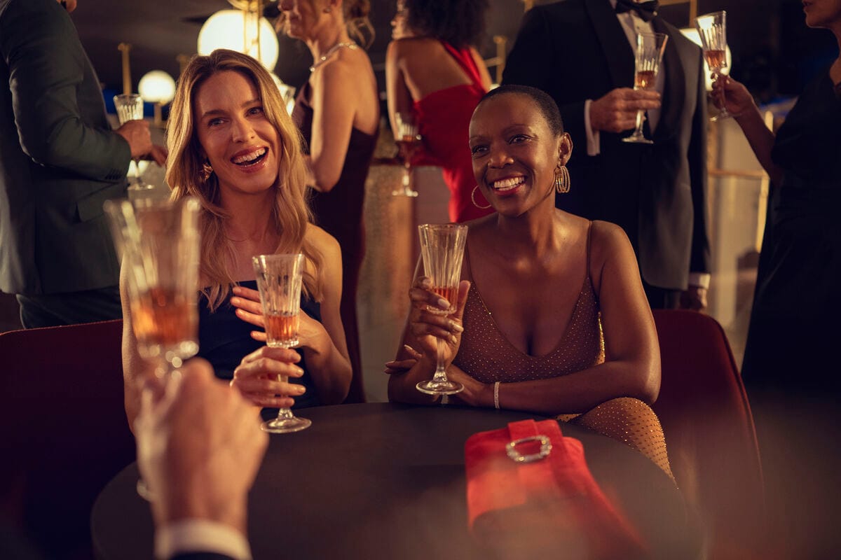 A couple sat at a small table enjoying drinks in eveningwear