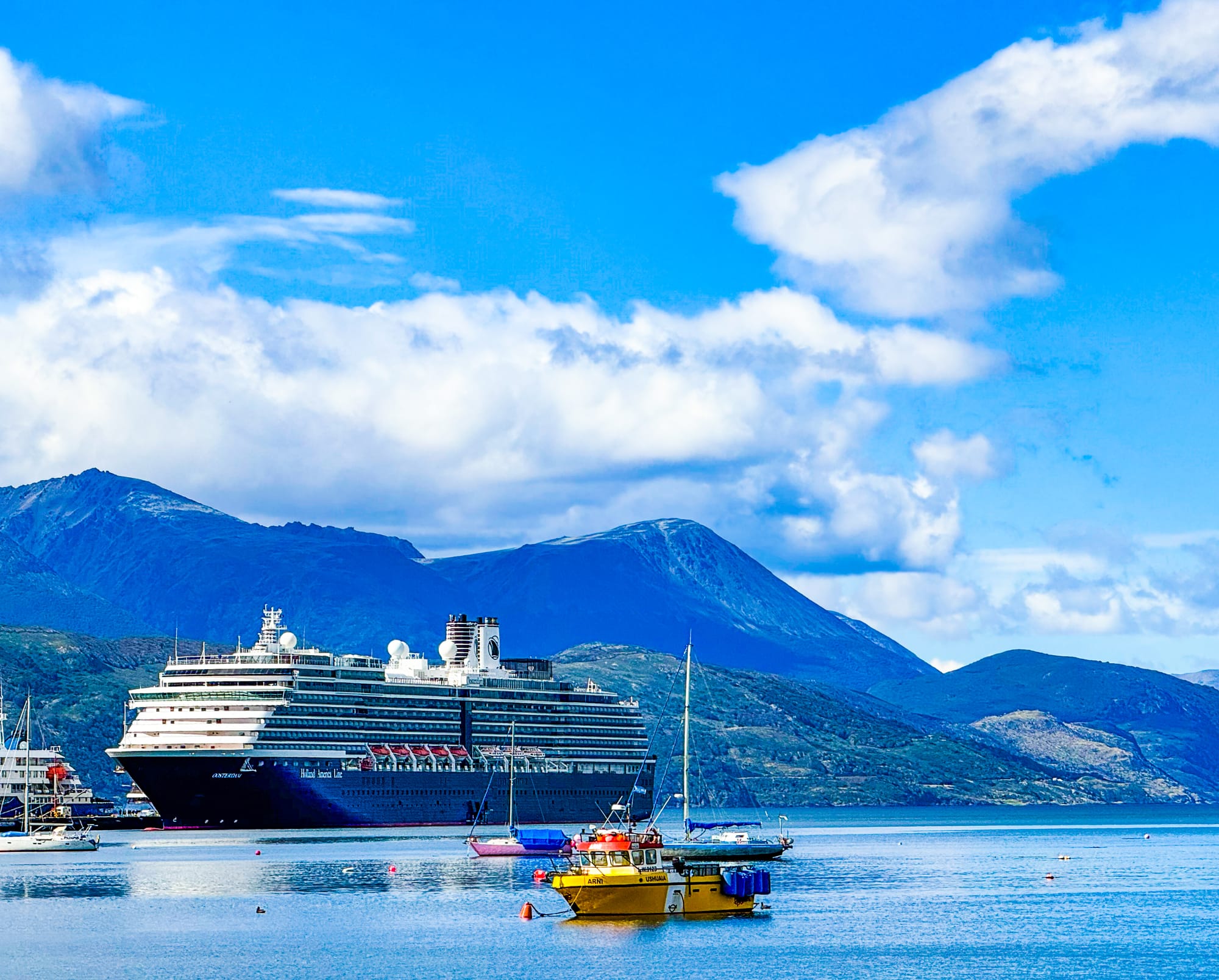 An image of Oosterdam docked in Argentina, with mountainous terrain in the background