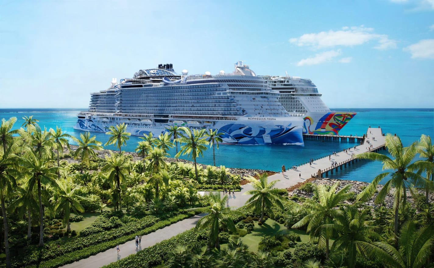 An image of two cruise ships docked at a pier with tropical foliage in the foreground
