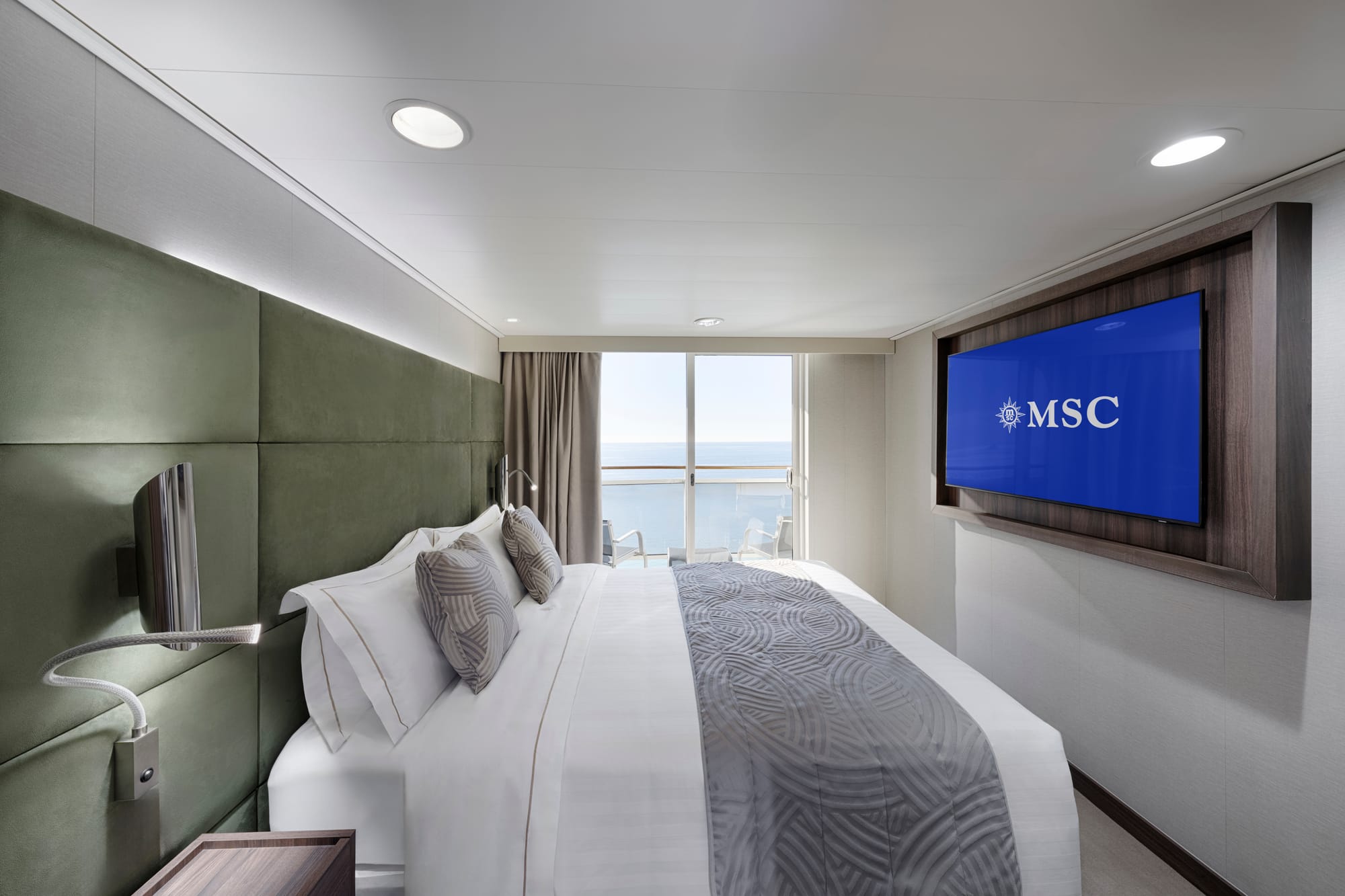 A bedroom with a double bed, a wall-mounted TV and a balcony
