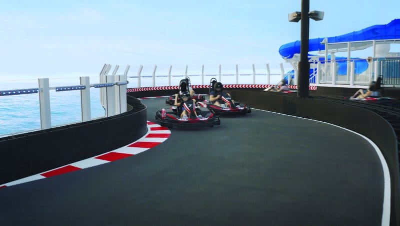 Two people racing electric go karts on a track on the top deck of a cruise ship