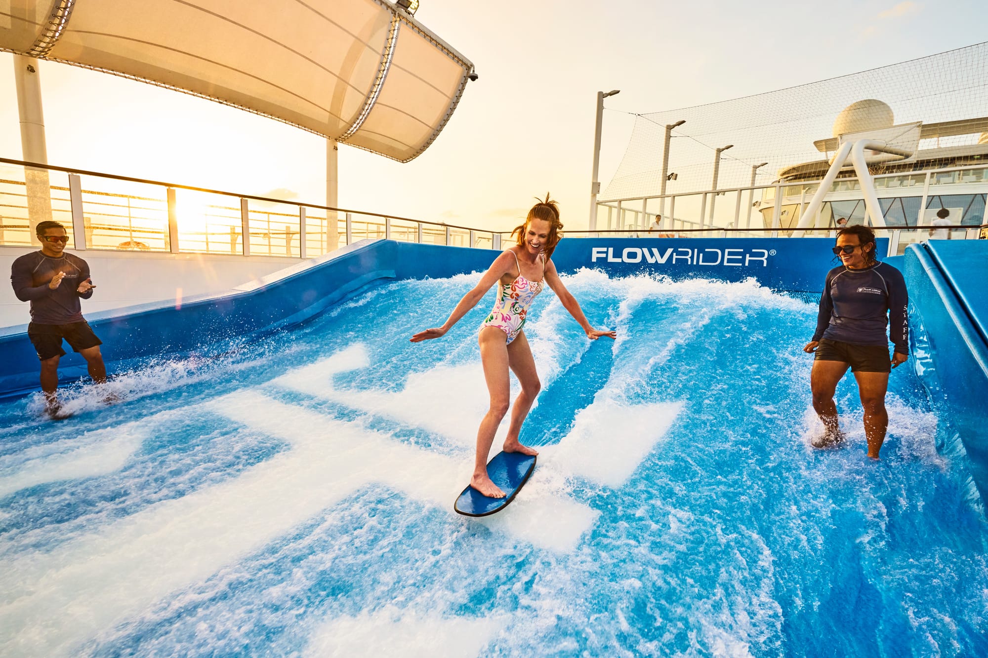 A woman on a surf simulator with two instructors