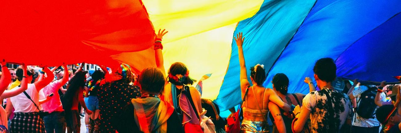 A Pride flag flying above a Pride parade