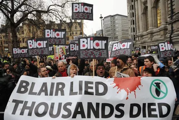 Protesters holding a banner that states "Blair lied, thousands died" with signs reading "Bliar"