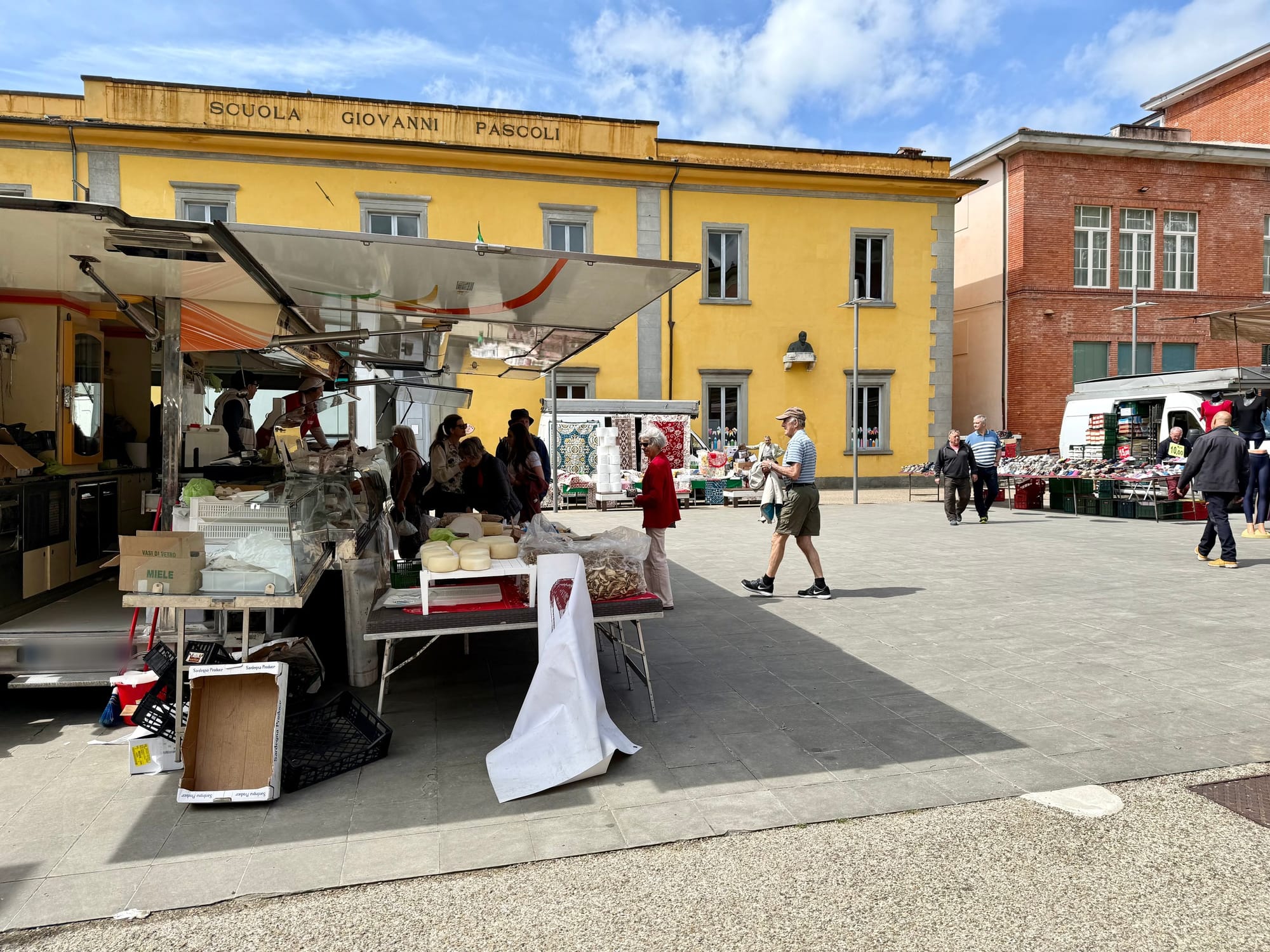 A mobile cheese and food truck with its side folded open at a Saturday market in Barga, Italy