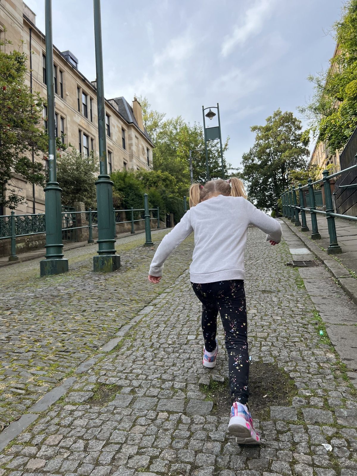 A young girl runs up a cobbled lane past tenement buildings in Mount Florida, Glasgow