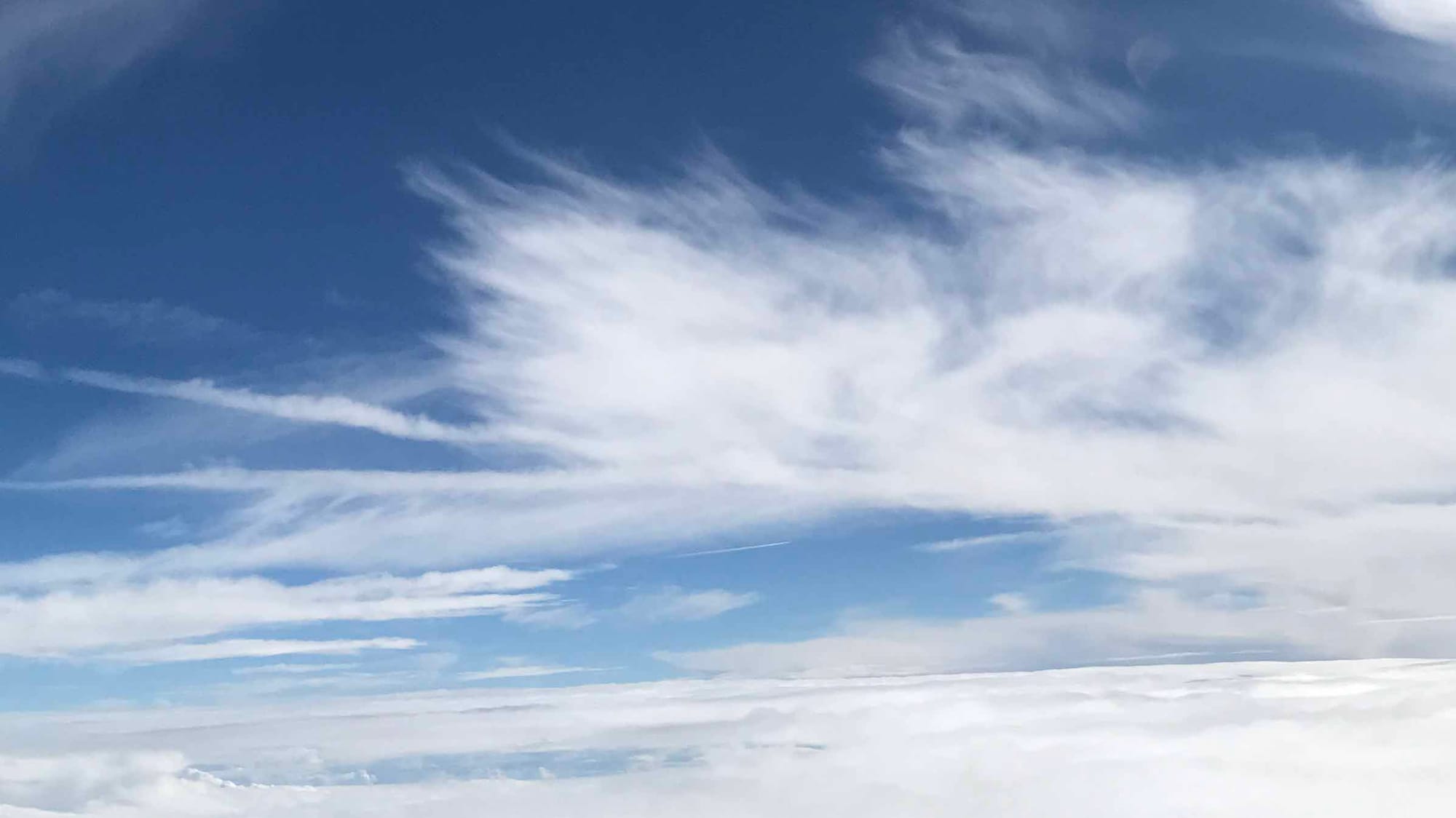 Feathery white clouds against a blue sky, with sheets of more clouds below.