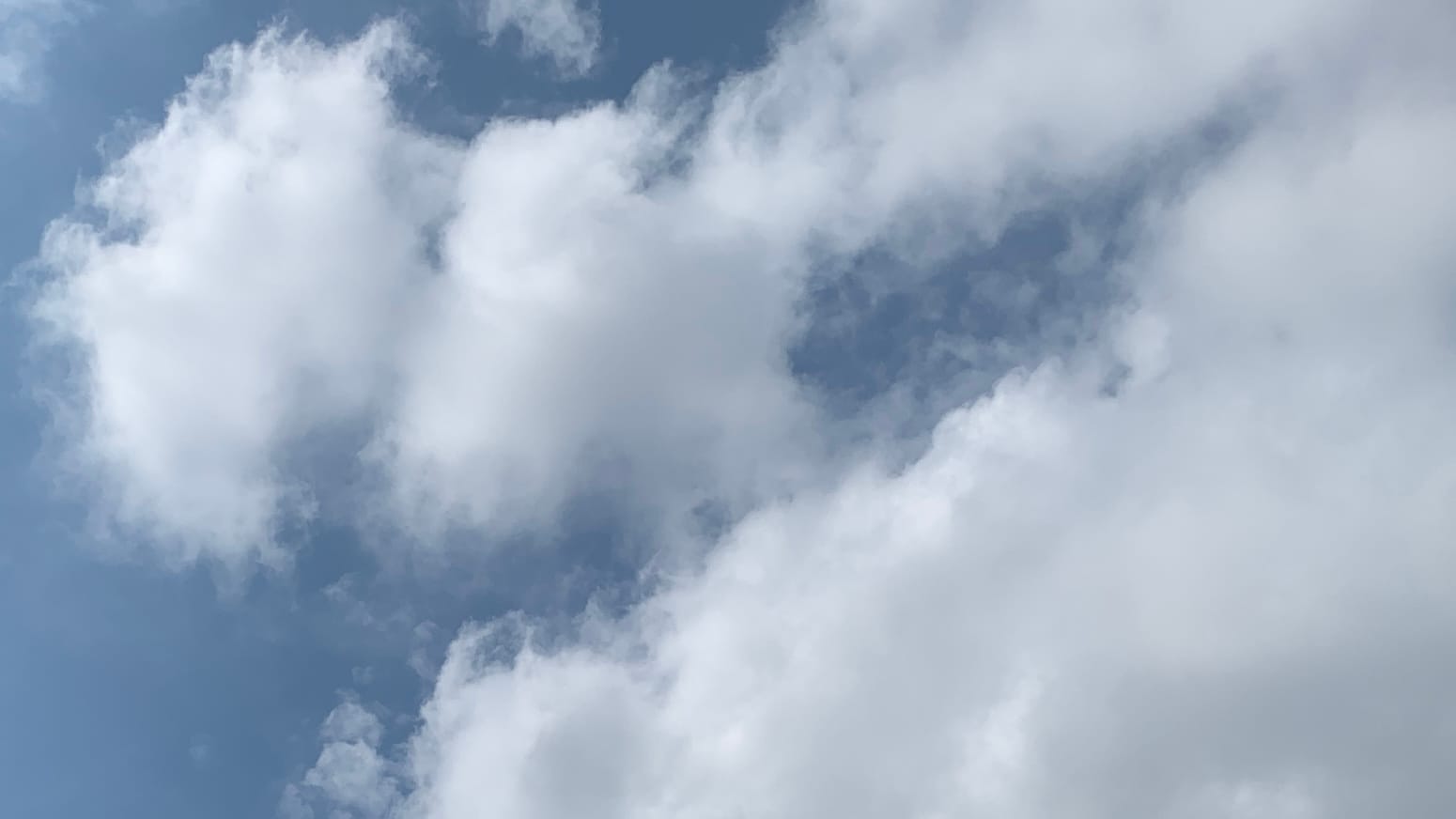 Mostly fluff-wisp clouds against thin blue sky