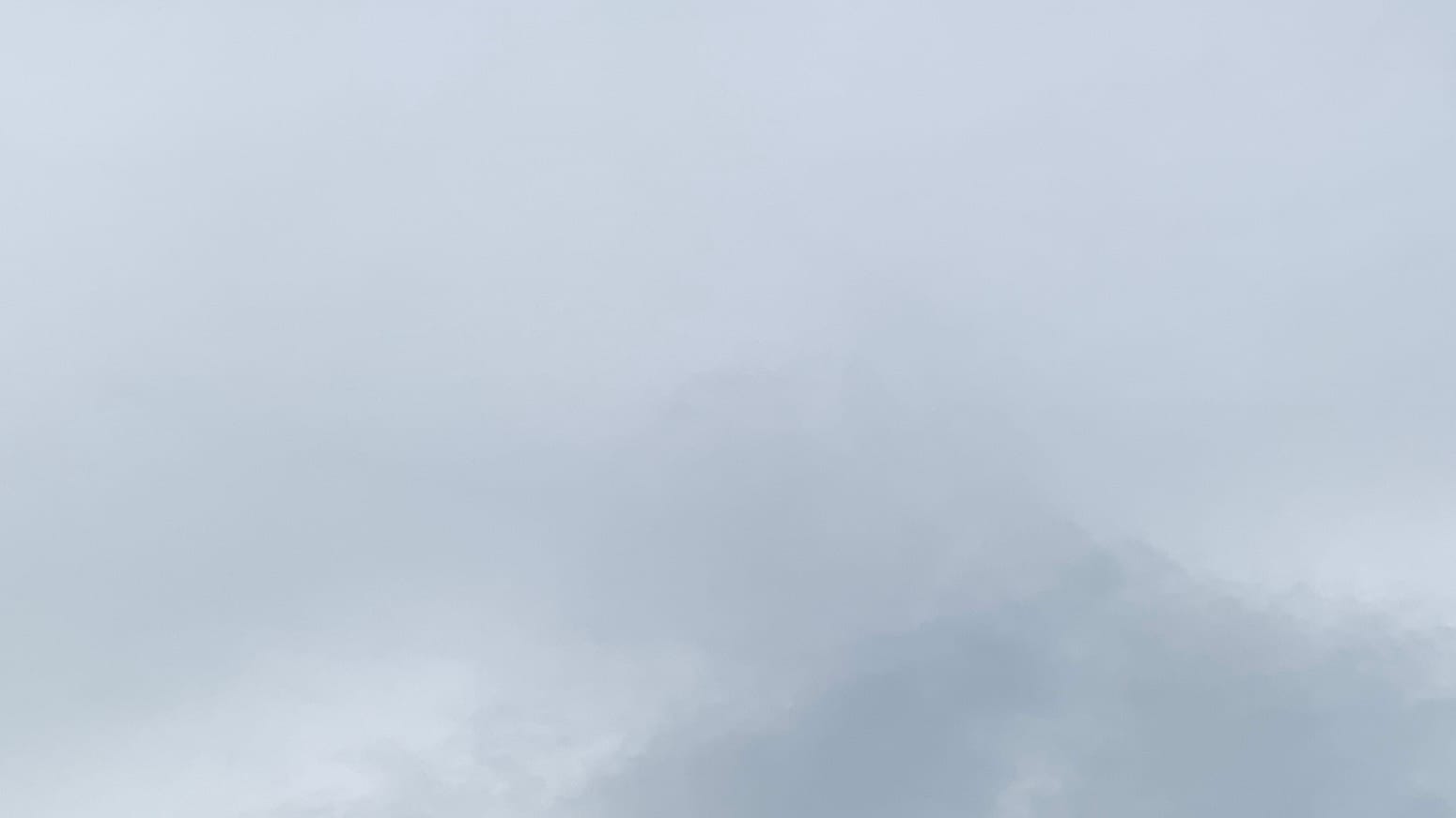 A patch of gray sky with some darker gray sticking up like a blurry mountain peak on the lower right-hand edge.