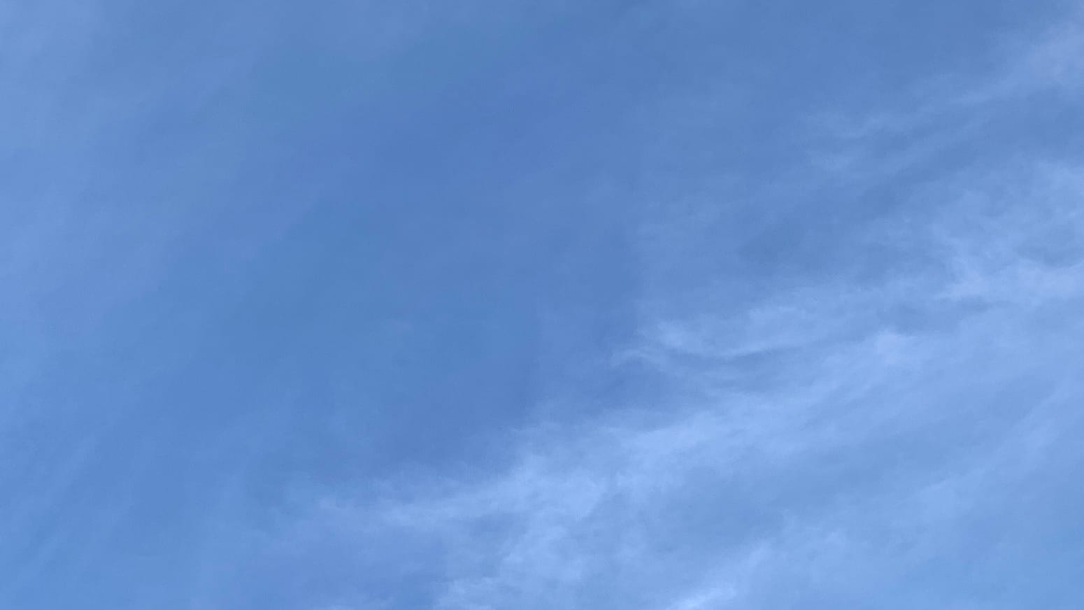 A patch of blue sky with wispy near-transparent clouds overlaid on it, most thickly in the lower right third of the frame.