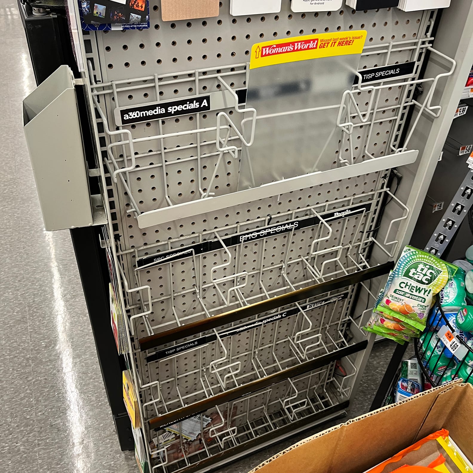 Empty wire rack at the checkout. tabs visible for 360 MEDIA SPECIALS, TISP SPECIALS, PEOPLE, AND WOMAN'S WORLD