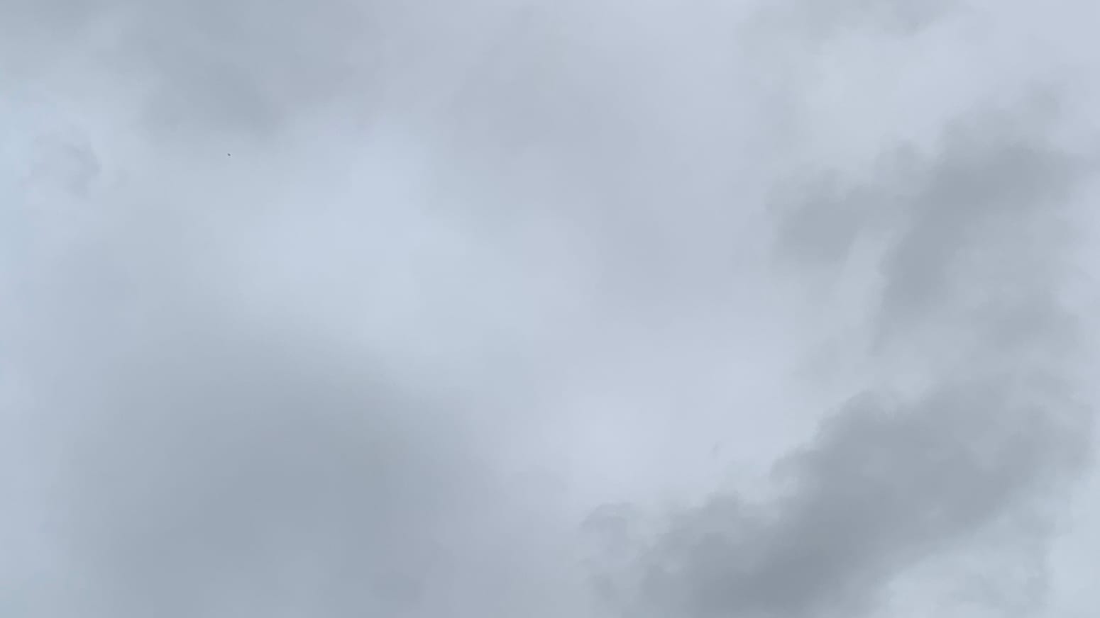 A patch of cloudy gray sky with lighter gray in the middle, blurry medium gray in the bottom left, and distinct loose clouds of darker gray across the bottom right corner.