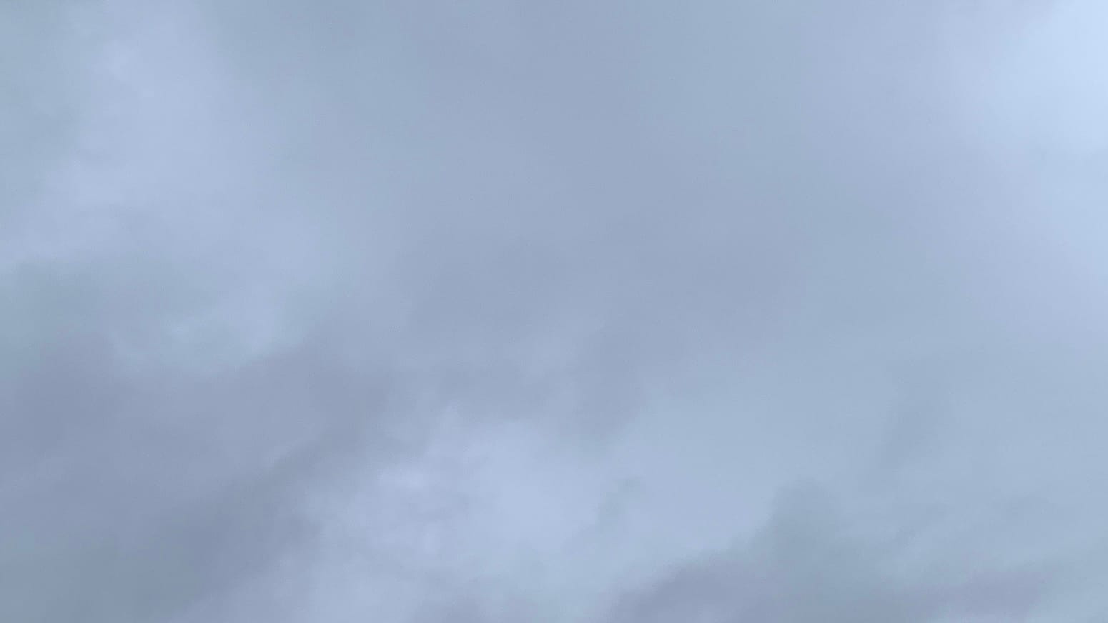 Alt: A patch of sky covered with a mix of light gray and medium gray clouds.