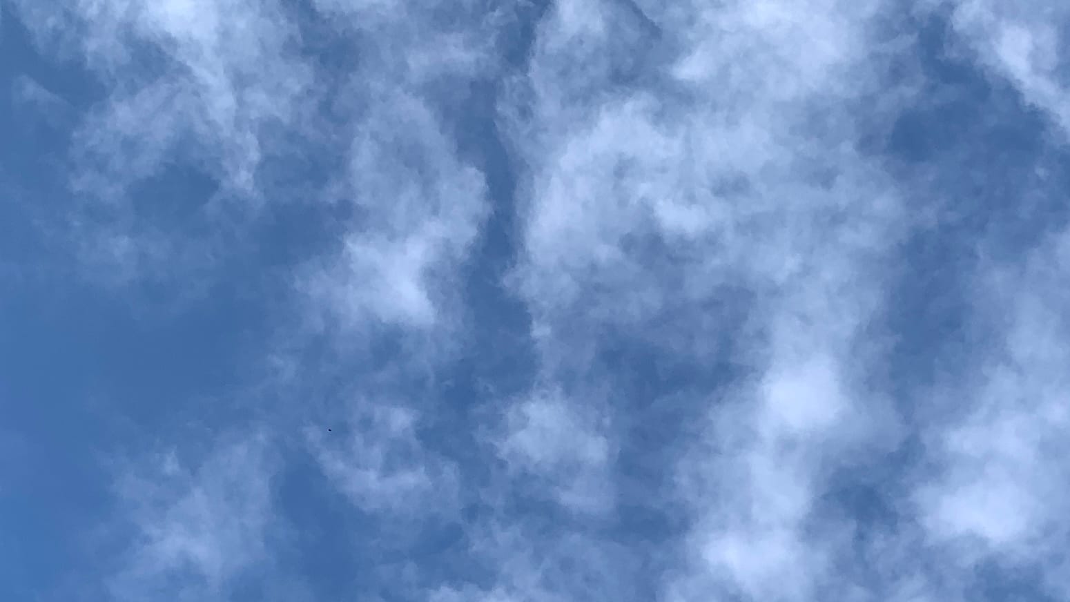 Alt: A patch of deep blue sky with thin wooly white cloud overlaid on it, with veins of blue running vertically through the cloud.