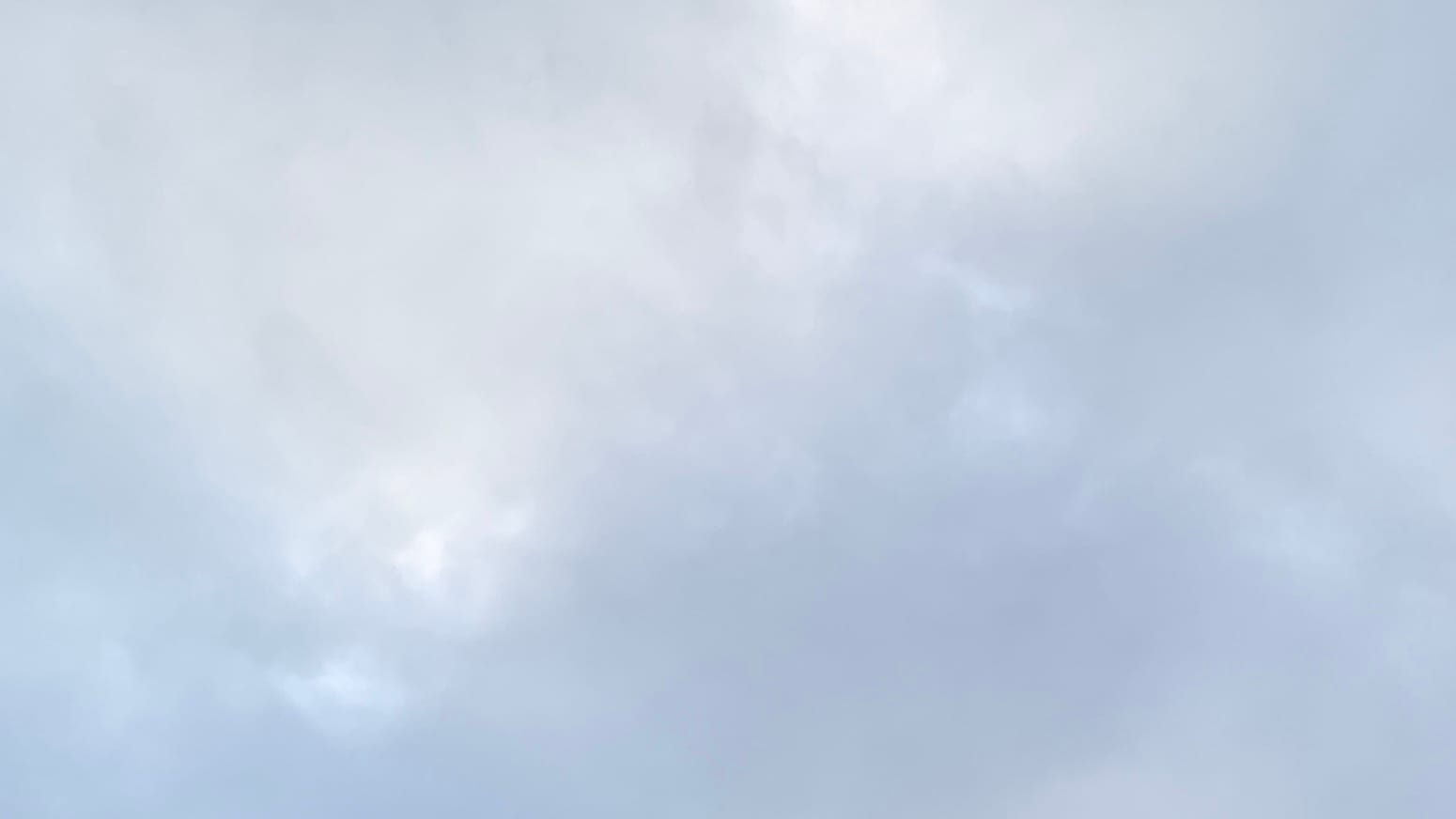 A patch of overcast sky with lustrous brighter spots showing through the indistinct cloud-forms. The clouds are smoother and grayer toward the bottom of the frame.