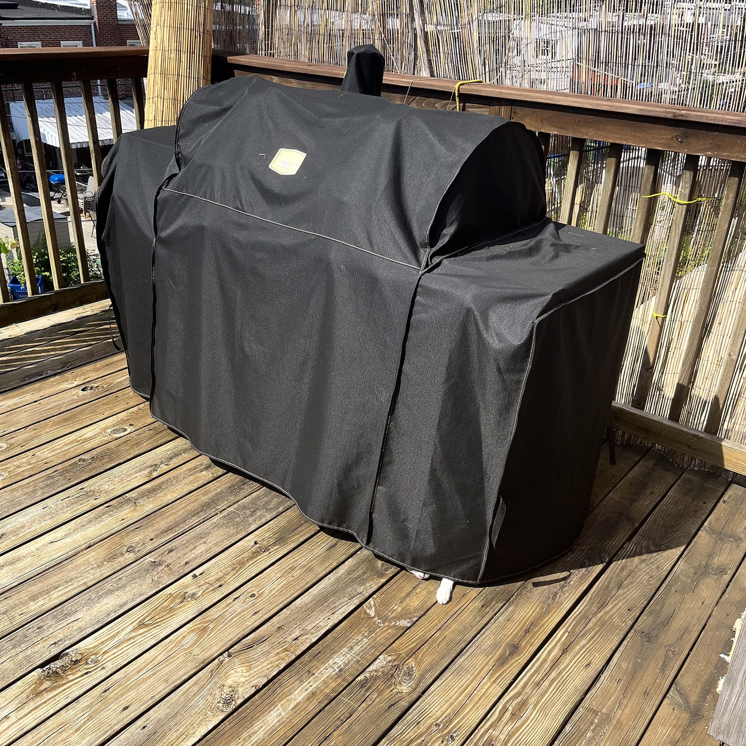 Grill with fabric cover and little cat paw and face sticking out at the bottom