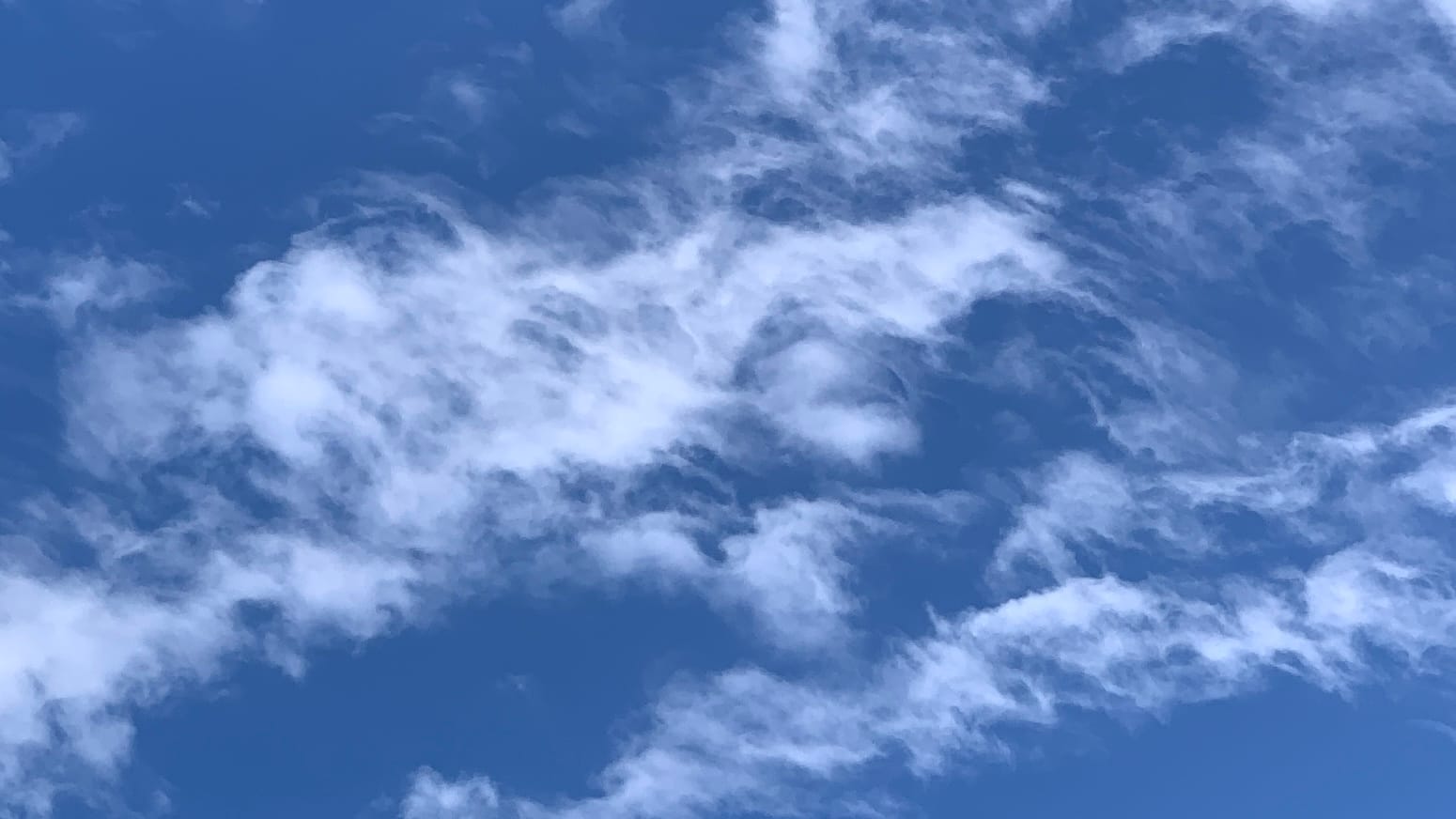 A deep blue sky with minced-up cirrus, probably formerly contrails, running over it. 