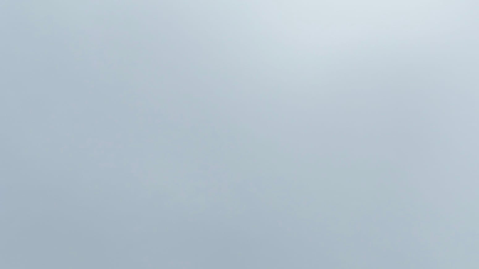 A patch of sky covered in smooth light gray clouds with subtly lighter parts toward the top right.