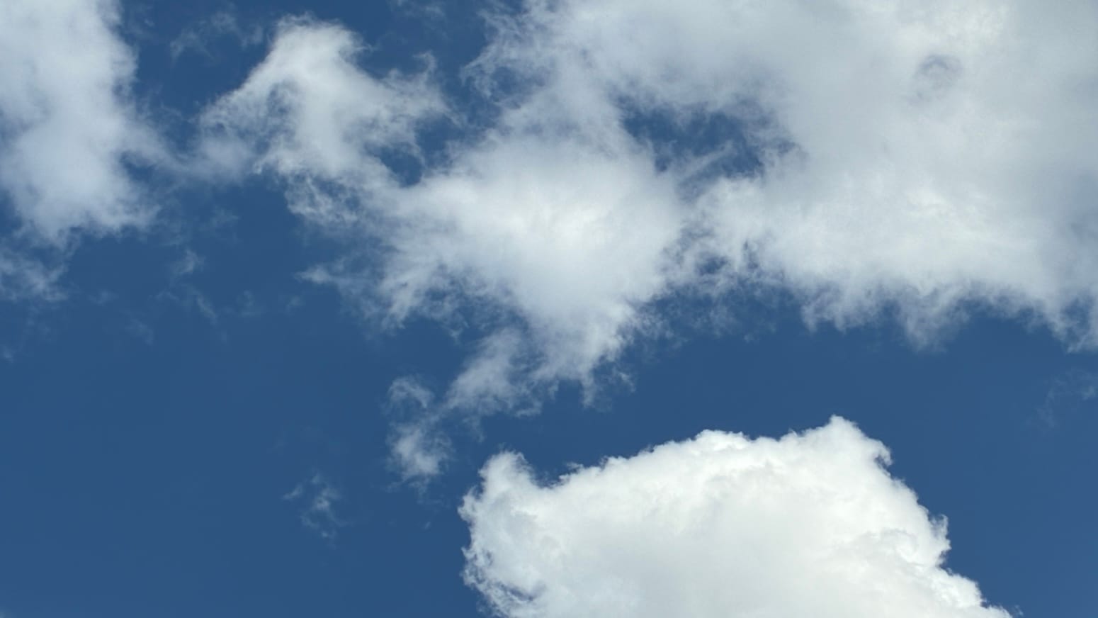 White clouds describe a sort of seacoast cut with gulfs and bays, with very deep blue sky playing the role of the water. 