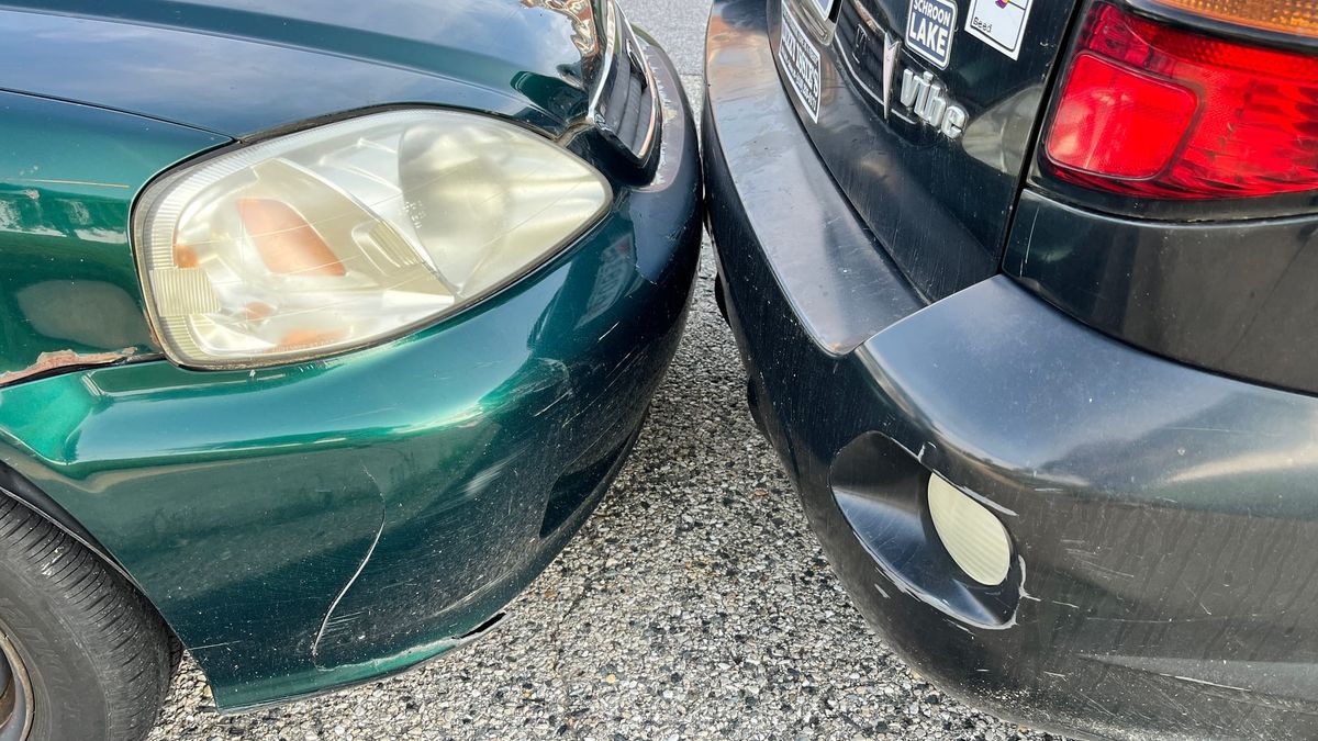 Two dinged-up cars kissing bumpers