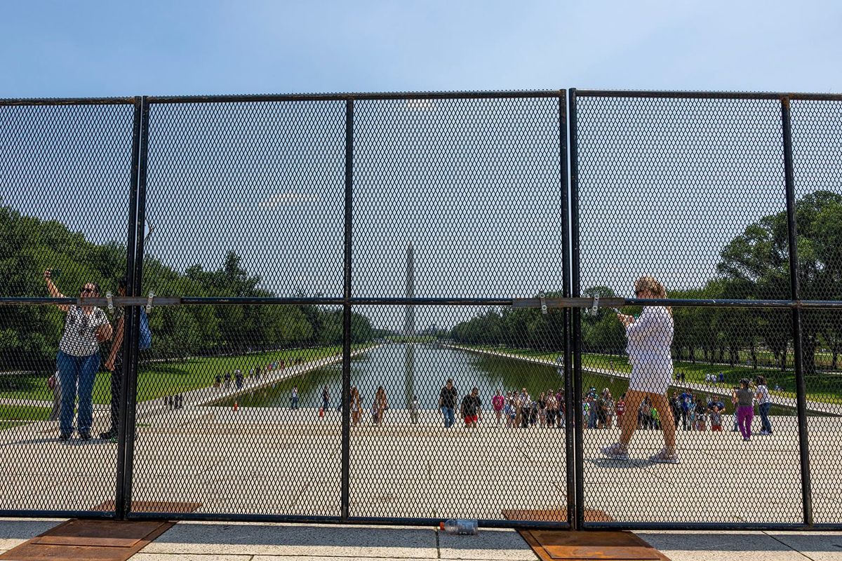 A tight-mesh fence obscuring the view of the Mall and the Washington Monument