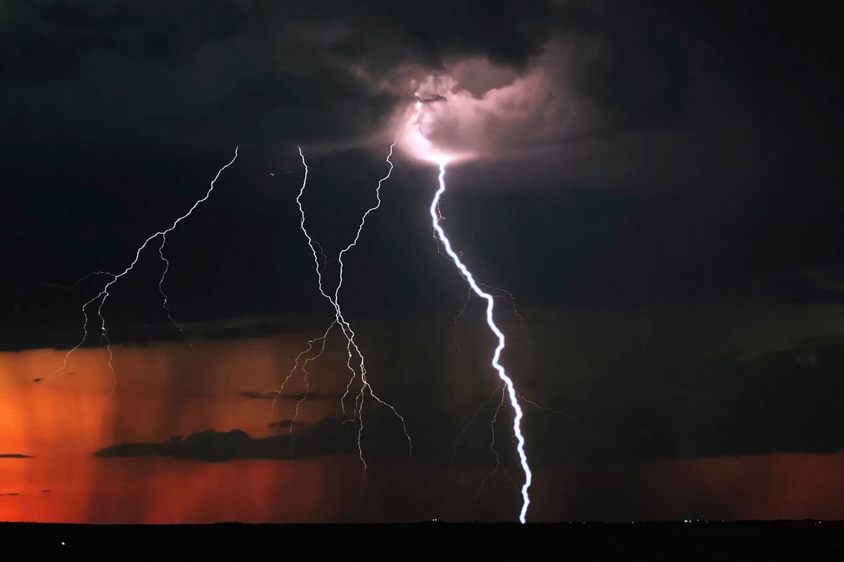 Multiple bolts of lightning against a dark sky and some of the bolts appear to be emanating from what looks like the moon behind roiling clouds but might be A HIGHER BEING