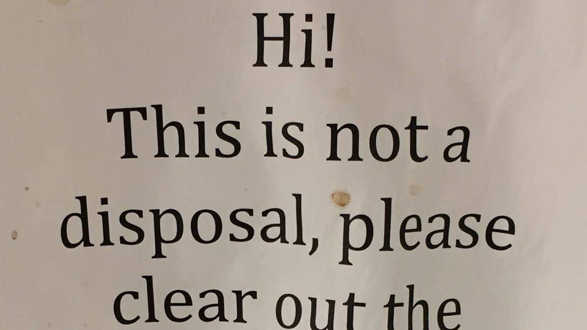 Fragment of a grimy, spattered office breakroom sign: HI! THIS IS NOT A DISPOSAL, PLEASE CLEAR OUT THE...