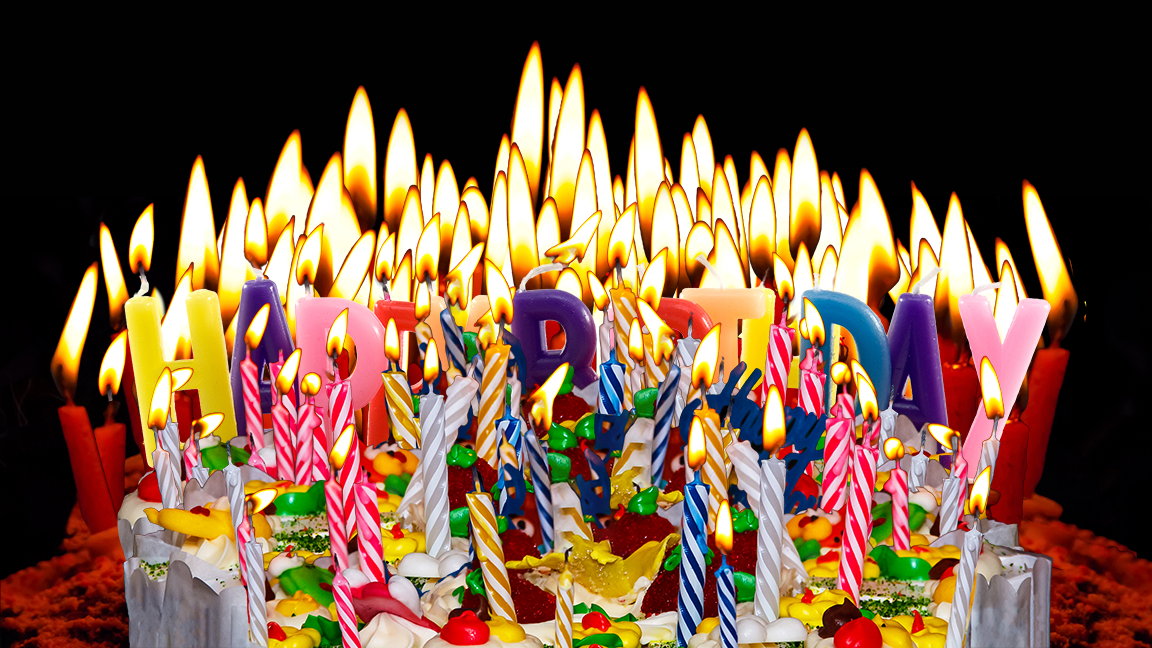 A gazillion birthday candles obscuring a cake as well as some letter-shaped candles spelling out HAPPY BIRTHDAY